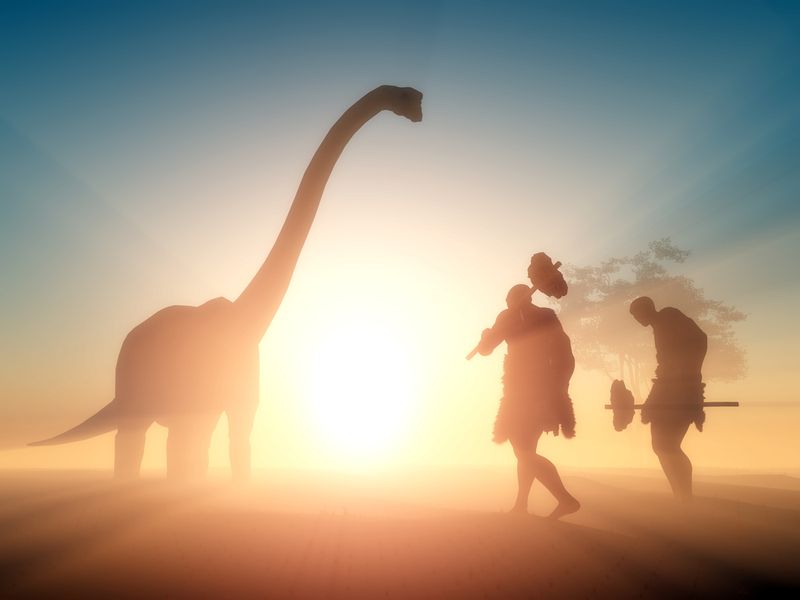 Silloute of caveman people walking towards a dinosaur in the sunset.