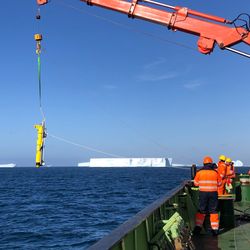 A robot glider gets hoisted off the side of the RRS James Cook boat.