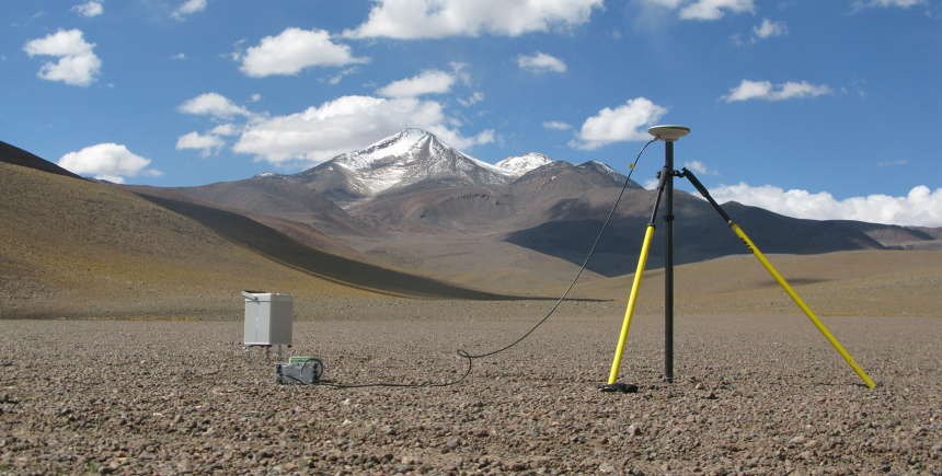 Fancy scientific equipment, including a gravimeter and GPS station, with Uturuncu looming in the background