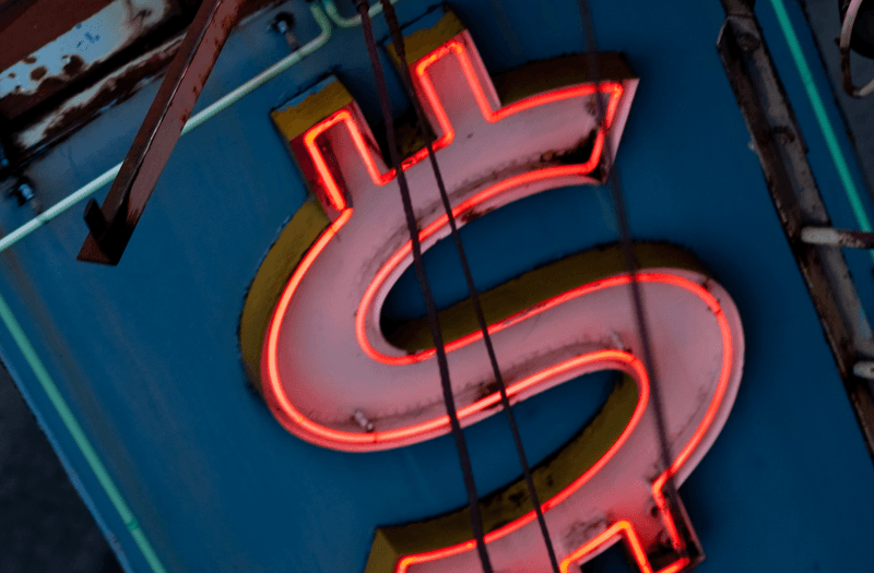 A neon light in the shape of an American dollar sign $$$$.